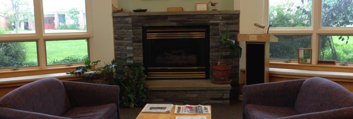 the fireplace room with sunlight shining in the windows and 3 purple chairs in front of the fireplace /end ID